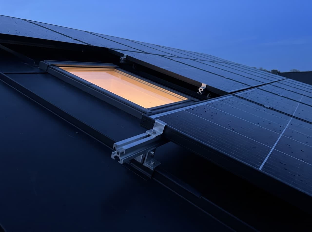 Symbolbild: Photovoltaikmodule auf einem dunklen Dach zur blauen Stunde
